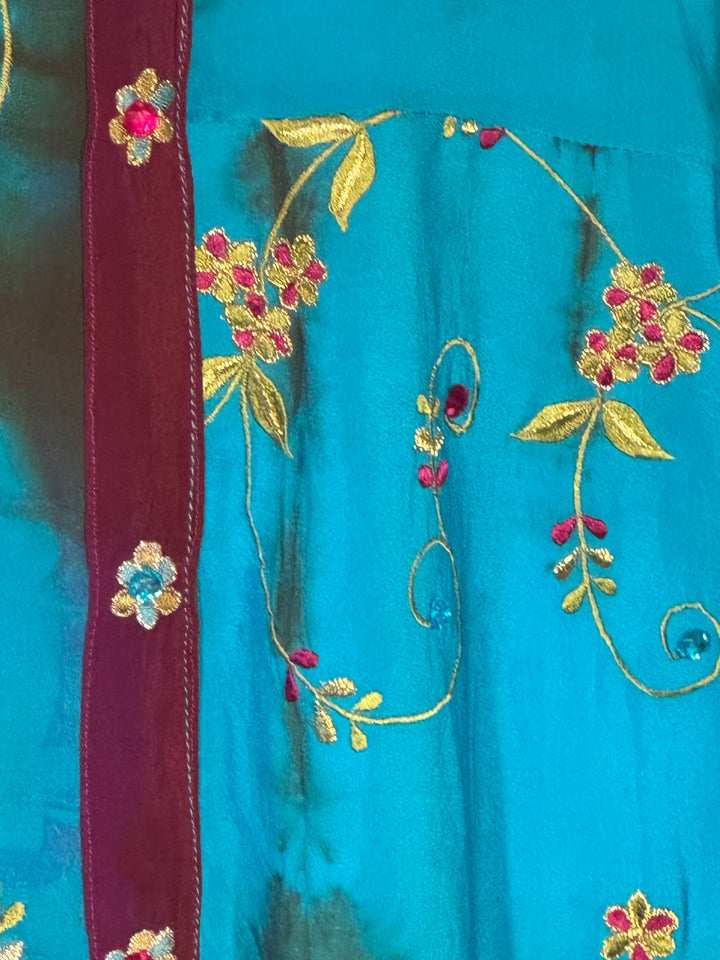 Close detail of blue dip dyed vintage silk with gold floral embroidery