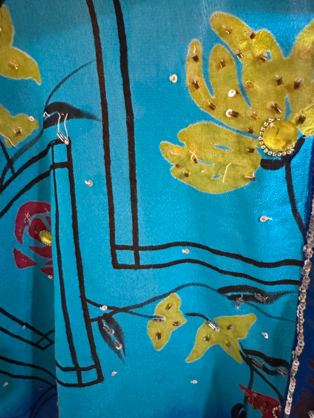 Close up of blue vintage silk with yellow flowers and gold sequins