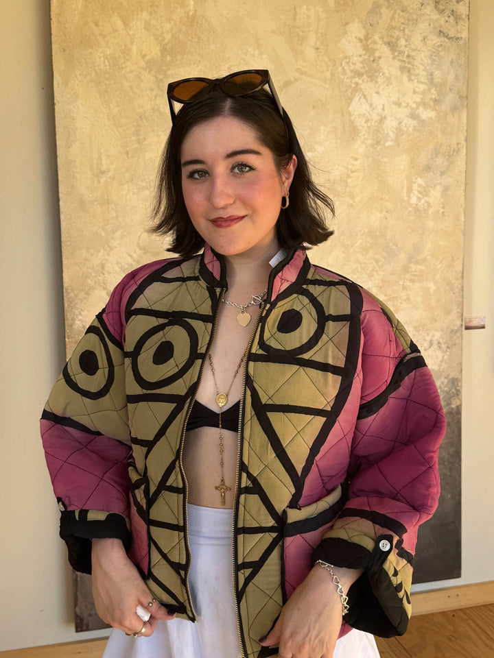 Dark haired model wearing pink and black quilted silk bomber jacket with white skirt