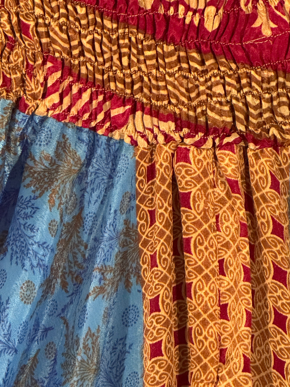 Close-up of patterned silk blend with red, gold, and royal blue colors.