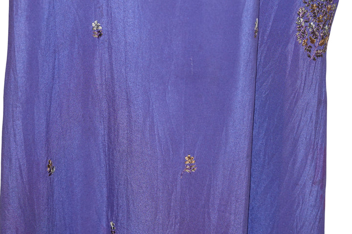 Close-up of blue dip dyed vintage silk fabric with floral embellishments on a white background