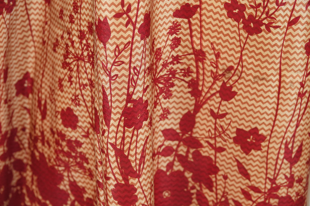 Close-up of vintage silk with red floral pattern on a orange background