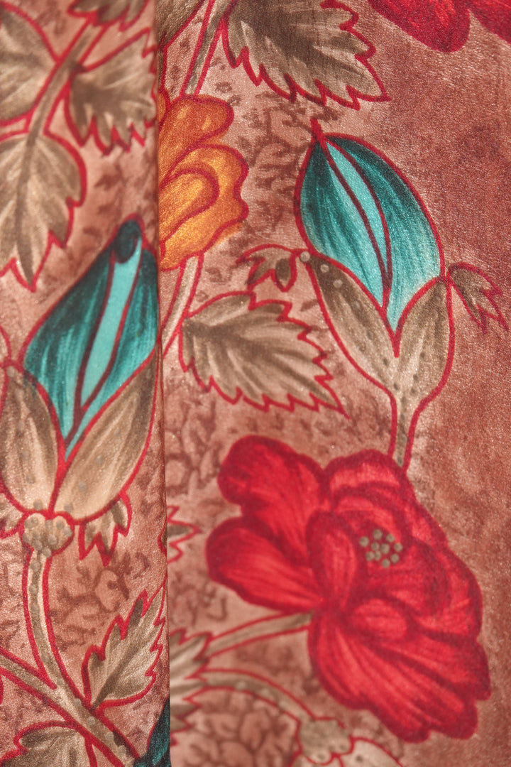 Close-up of a floral vintage silk with red, blue, and orange flowers on a brown background.