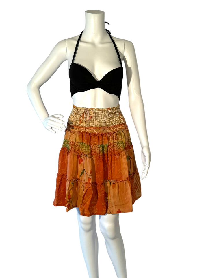 Mannequin wearing vintage silk gathered elastic short tiered skirt in orange with green floral print