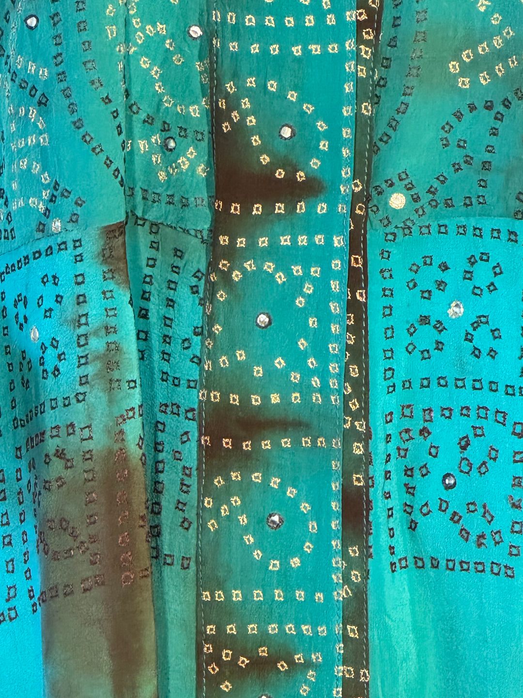 Edge view of vintage silk in blue green dip dye with small pattern of metallic sequins