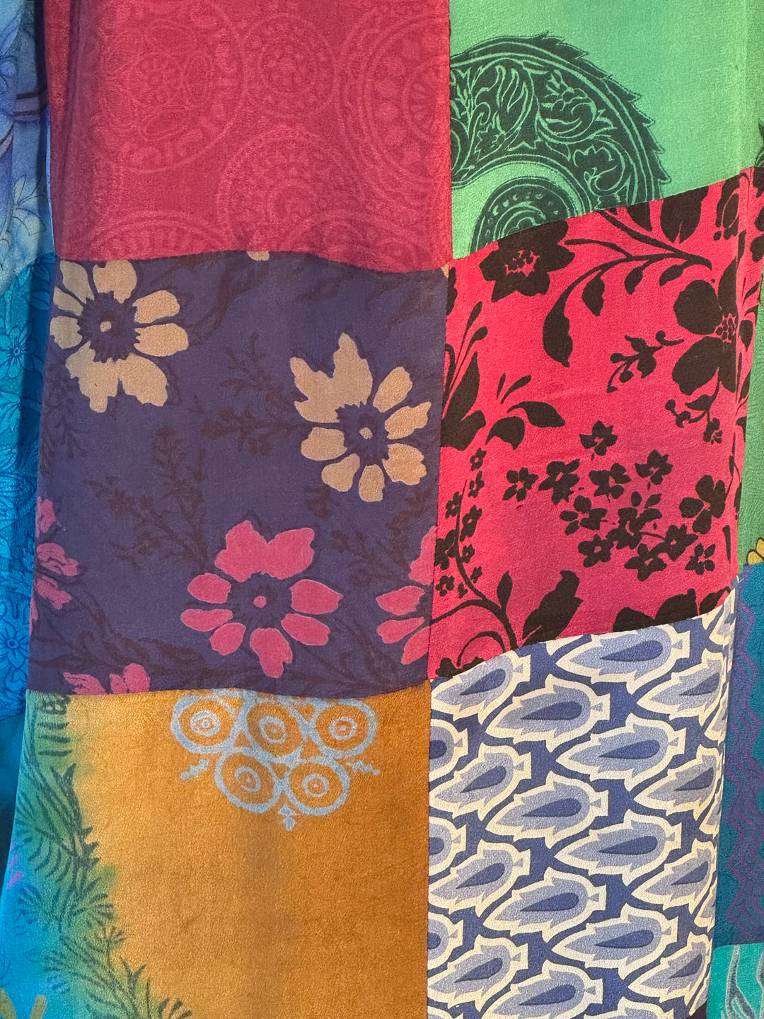 Close up of multiple vintage silks used in patchwork kimono in reds, greens, blues and golds