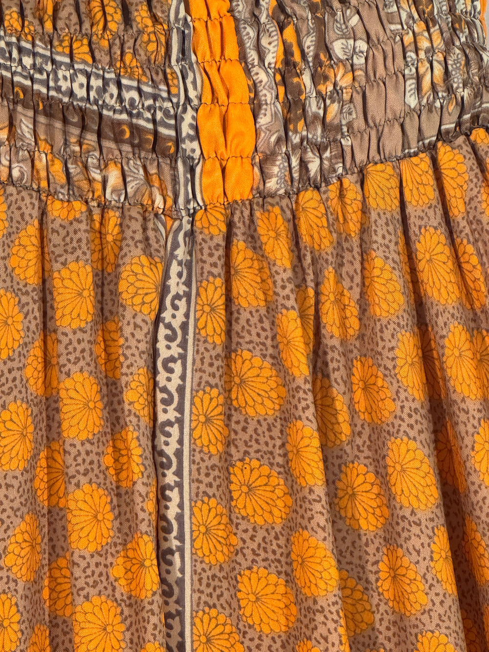 Yellow silk blend fabric with paisley patterns and decorative border close up