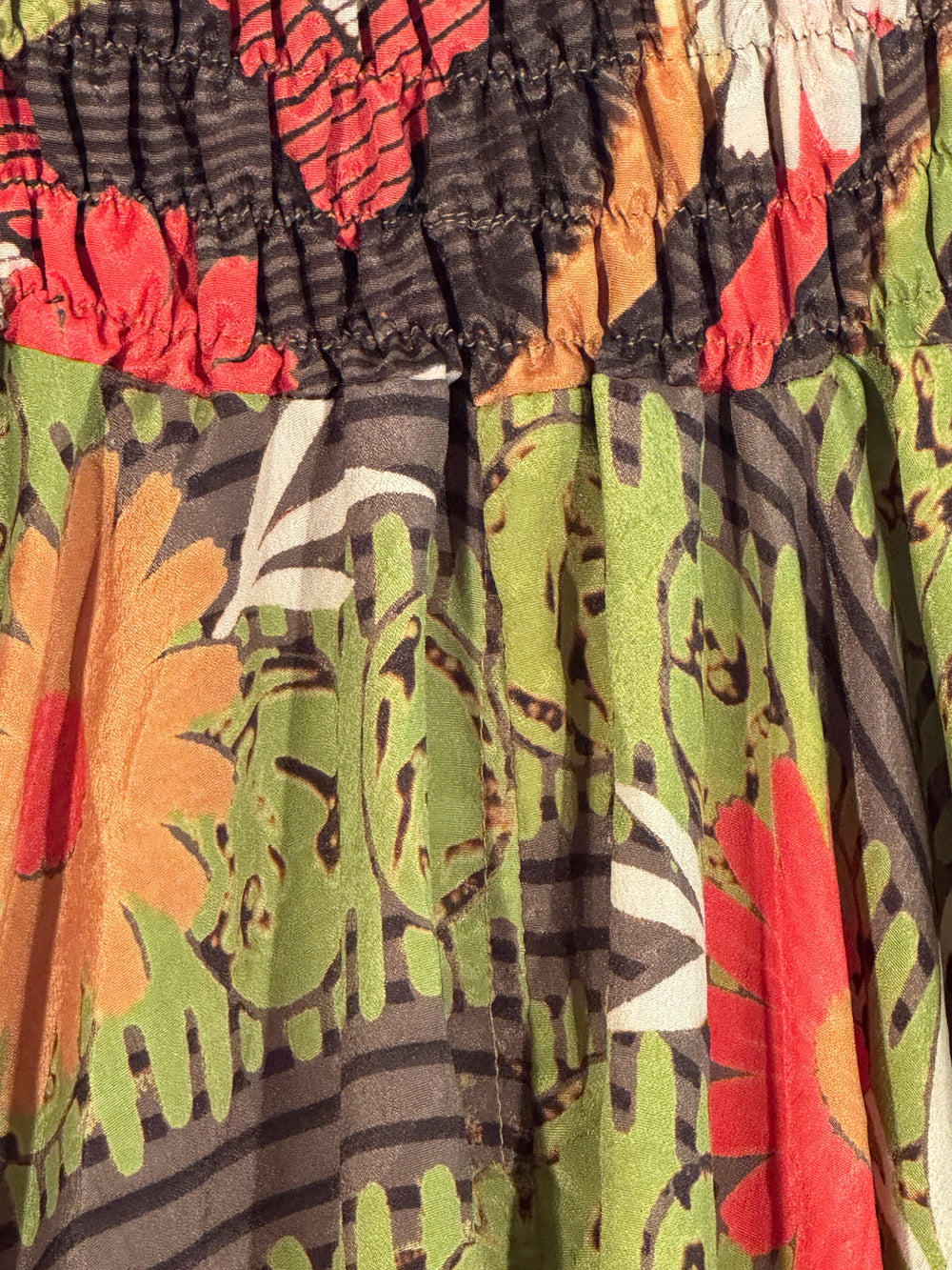 Close-up of silk blend with tropical leaf pattern in red, green, and brown.
