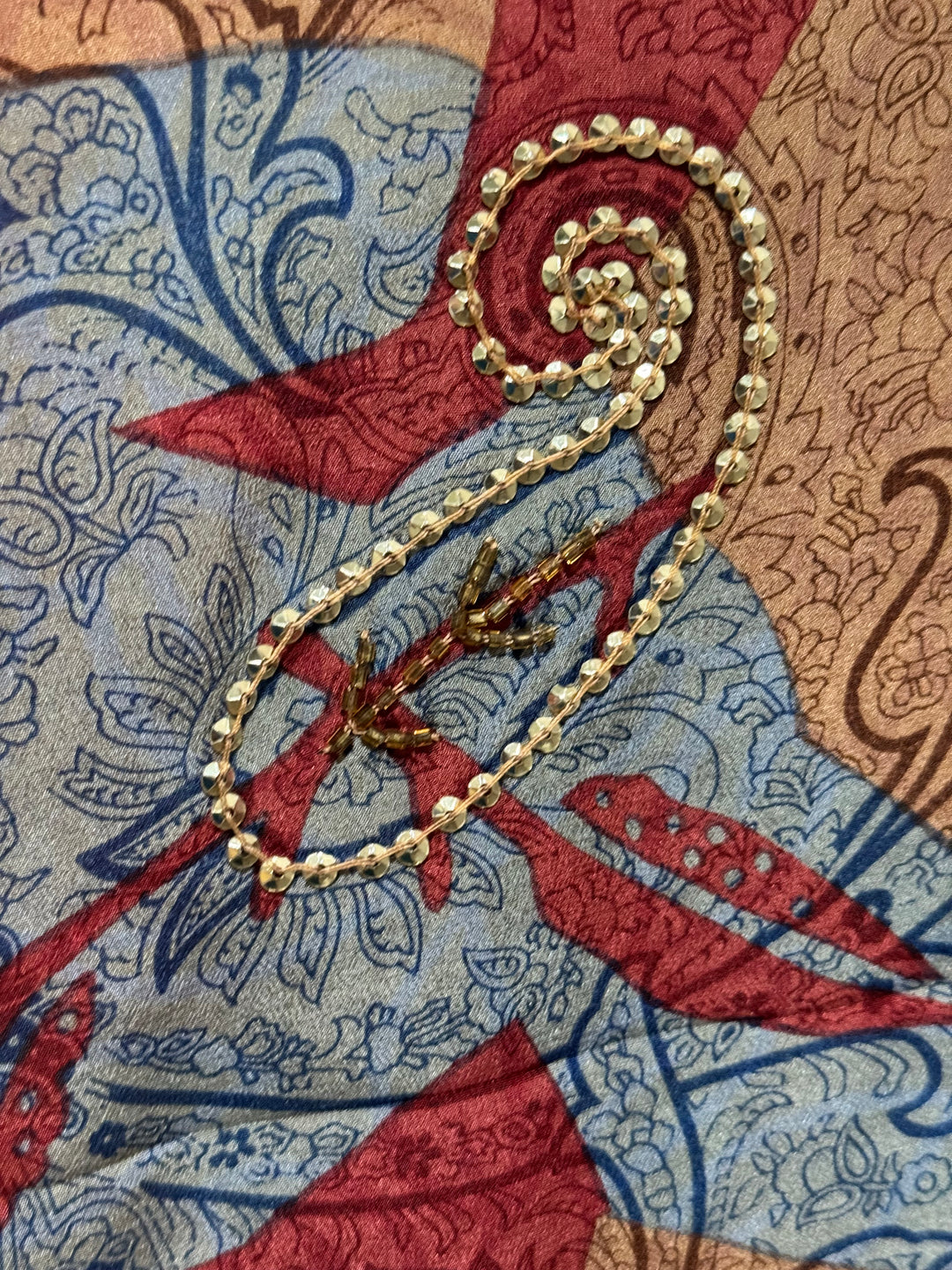 Detail view of vintage silk Willow Wrap in red, gold and gray with large paisley print and gold sequins